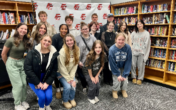 A group of students pose in the library