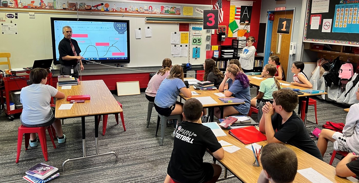 A teacher with a rope demonstrating waves to a classroom of students.