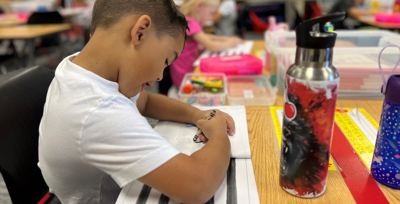 A student sitting at a desk working on a writing assignment.