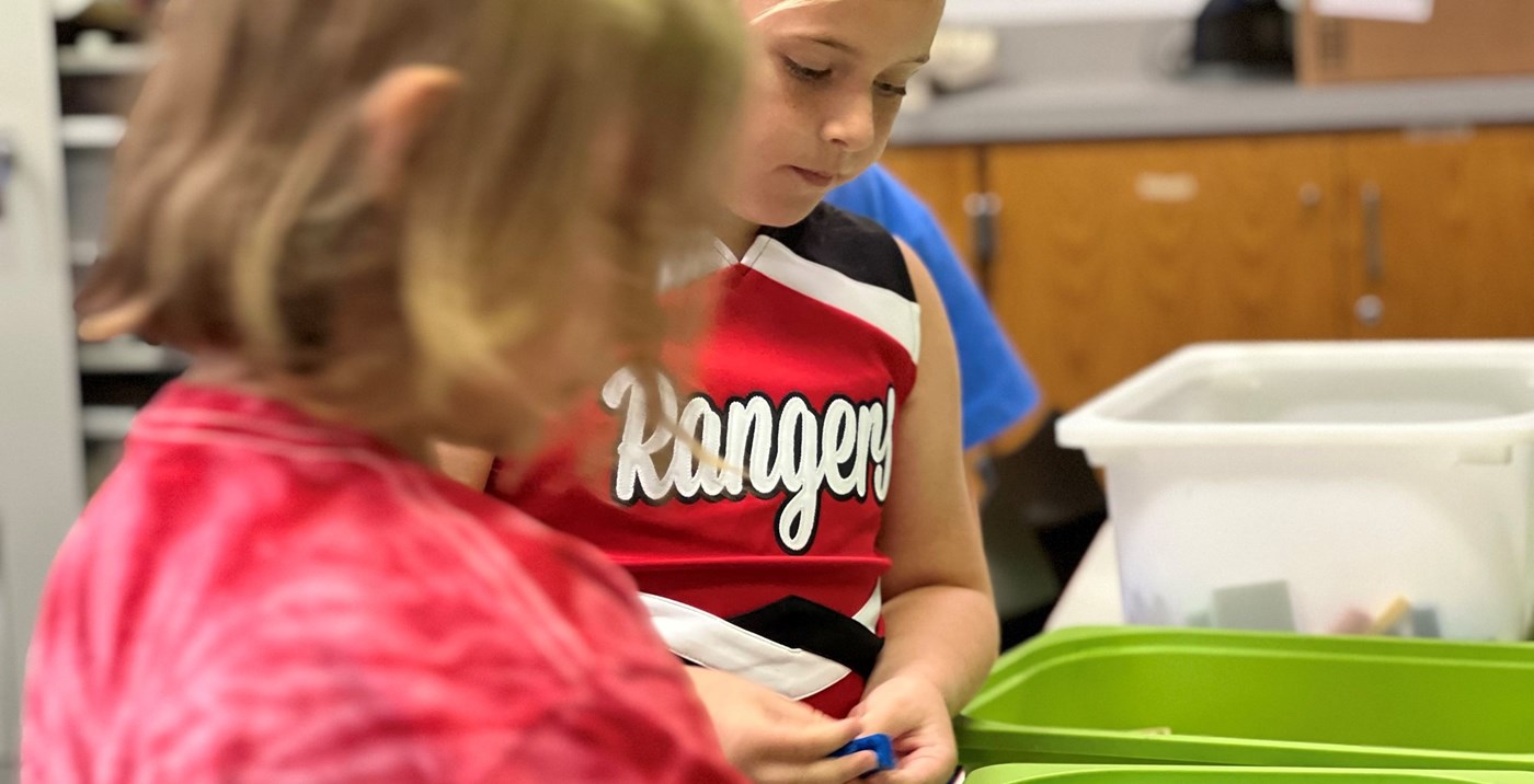 A student in a cheerleading uniform playing with Legos