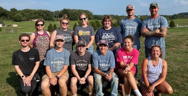A group of students and adults posing for a picture on a farm